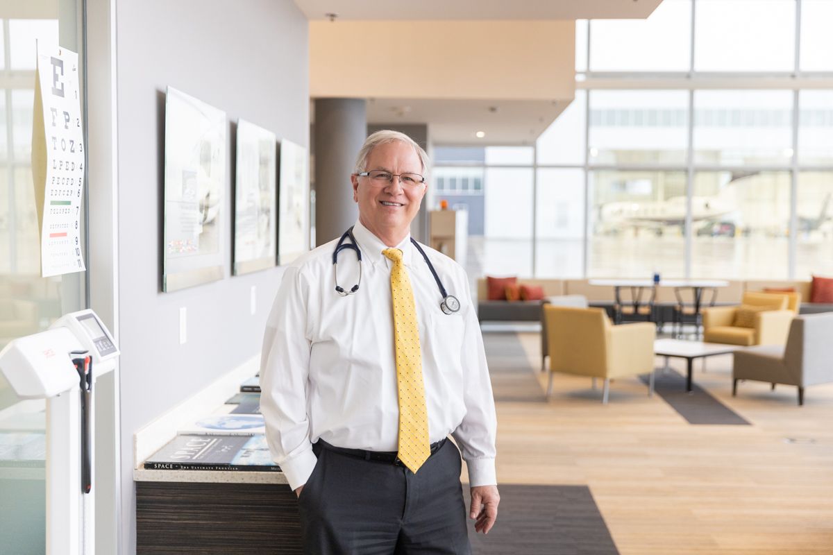 Dr. Edmondson in the exam area at Gerald R. Ford International Airport, with the eye chart and scale used during the exam