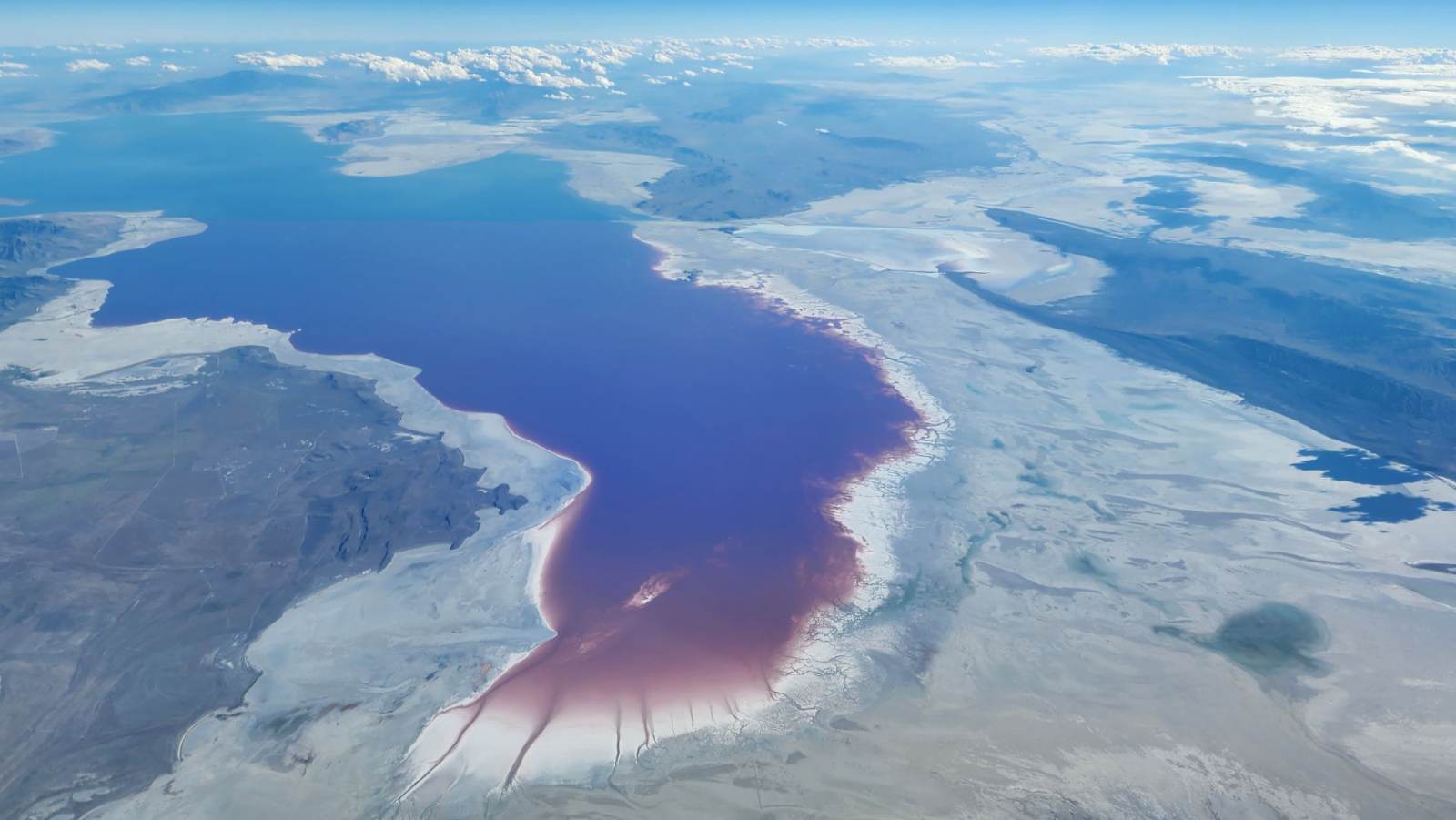 The Great Salt Lake from cruise altitude, its north arm split pink and deep blue by the causeway