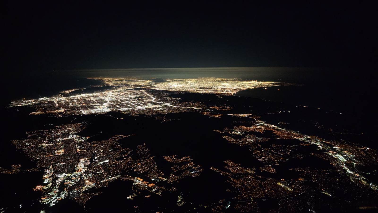 City lights along the coast seen from the flight deck at night