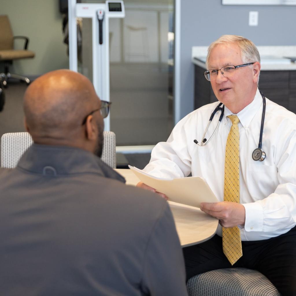 Doctor conducting an FAA medical exam, sitting at a table and talking to a pilot during an AME examination.
